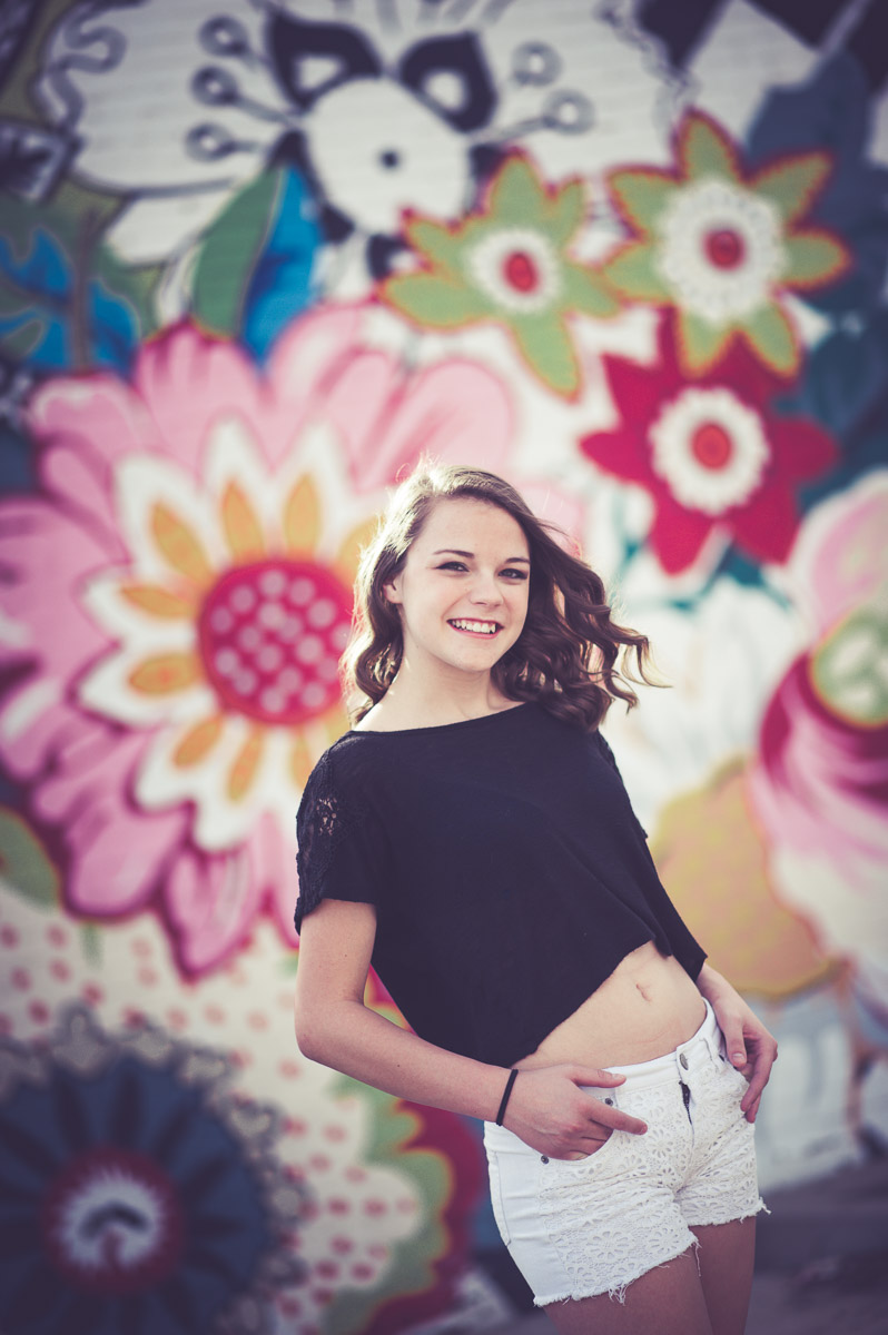 Senior portrait of a girl in front of a flower painted wall in evansville indiana